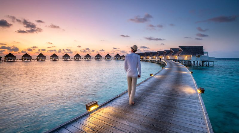 An image of a man walking along a bridge over a lagoon at sunset to support luxury travel article