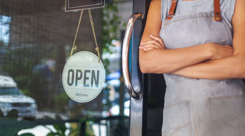 Image of a person leant up against a glass door to a cafe with an 'open' sign displayed to support future of small business article