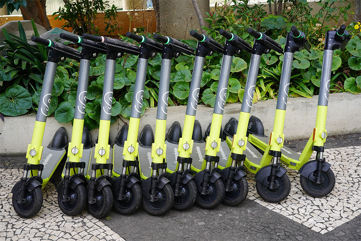 Image of yellow and black push scooters lined up in a row in a park to support superpedestrian article