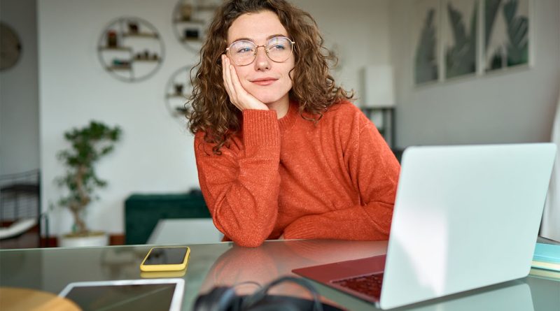 Image of a woman sat in front of a laptop at a desk appearing to be staring into space to support business productivity article