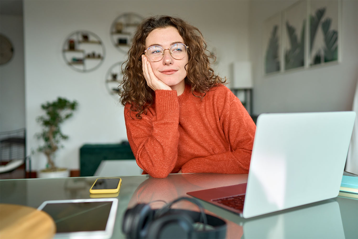 Image of a woman sat in front of a laptop at a desk appearing to be staring into space to support business productivity article