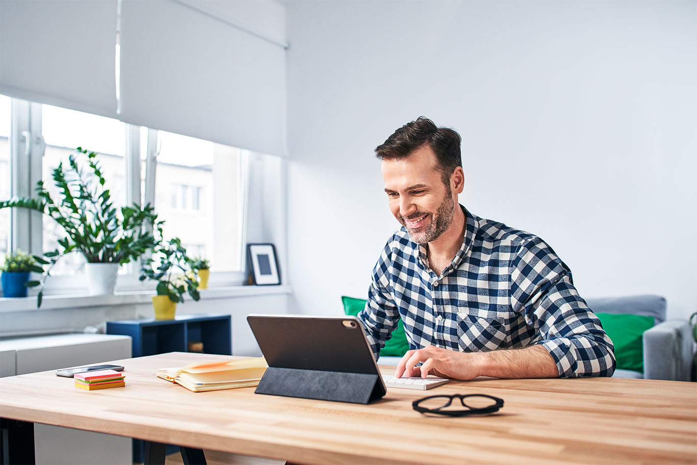 Image of a man working in front of a laptop on a desk in home environment to support remote work article