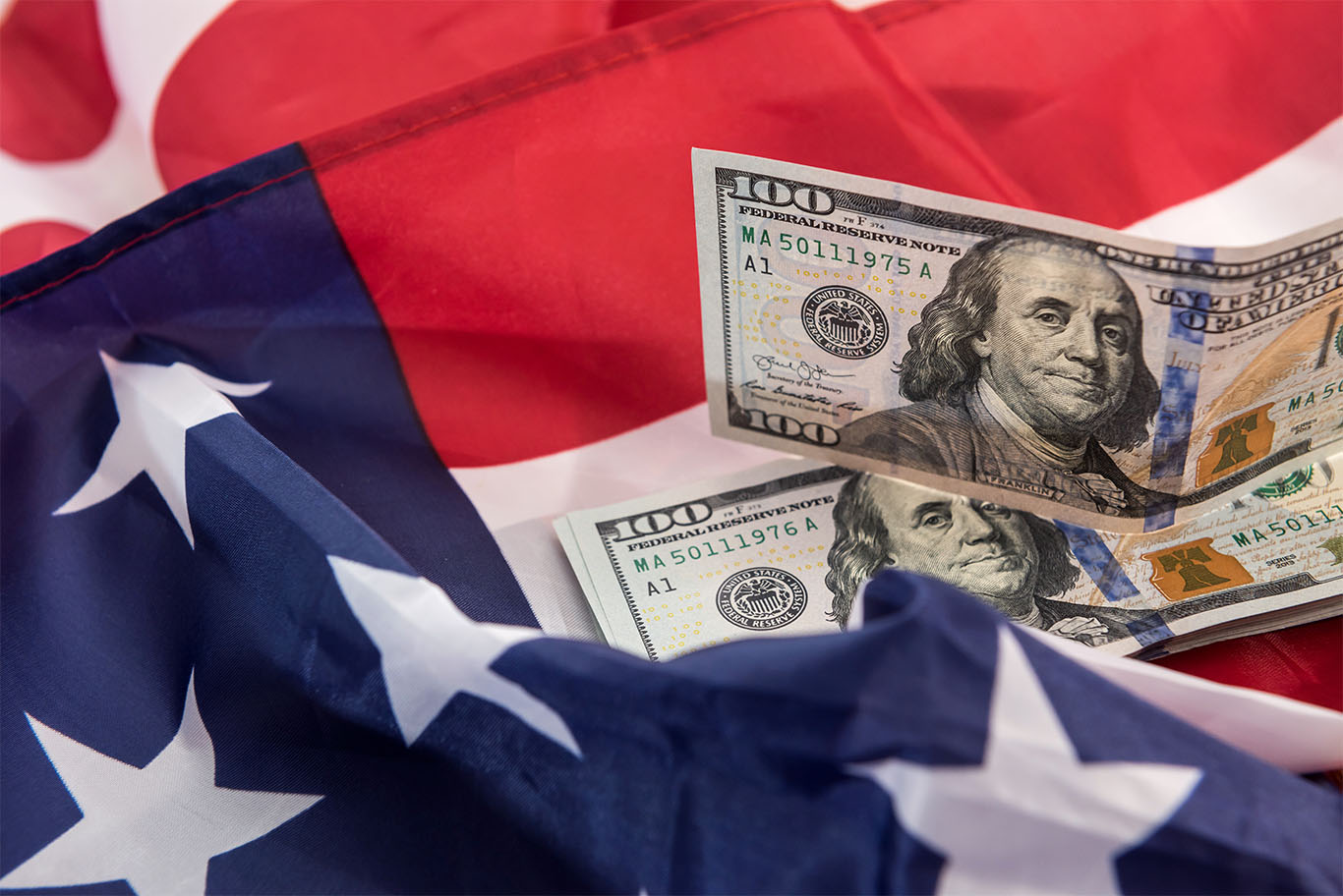 Image of the American flag with two dollar bills laid on it to support US economy article