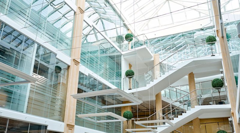 Wide-span image of an open-space modern office with glass walls and white staircases to support WeWork article