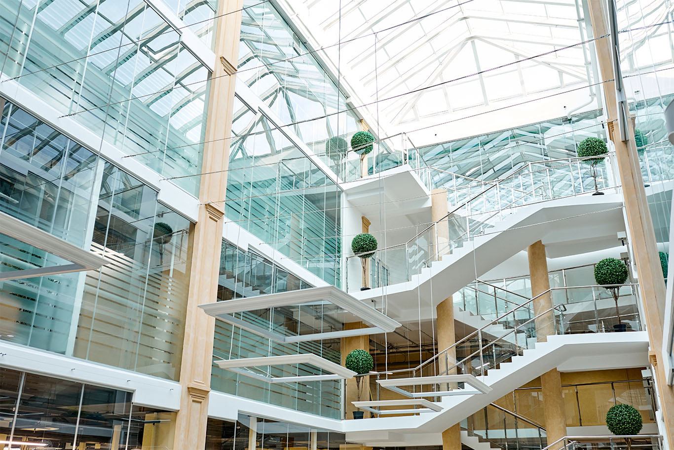 Wide-span image of an open-space modern office with glass walls and white staircases to support WeWork article