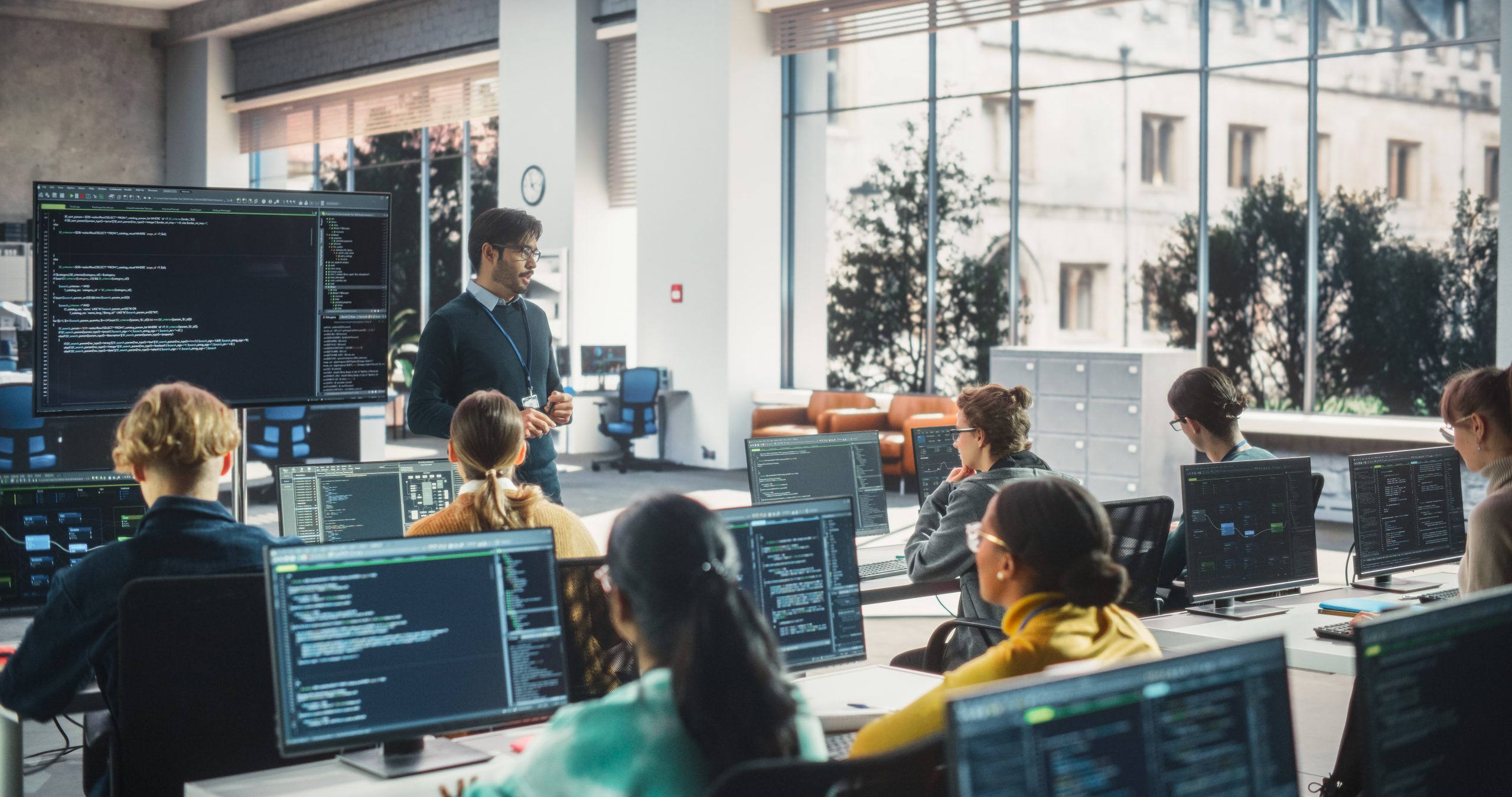 A modern digital classroom with diverse students engaged in education, using technology and guided by a teacher.