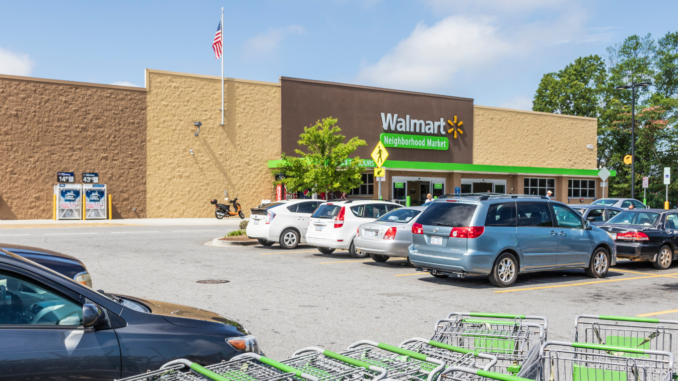 Walmart Neighborhood Market storefront, a successful family business, with parked cars and shopping carts.
