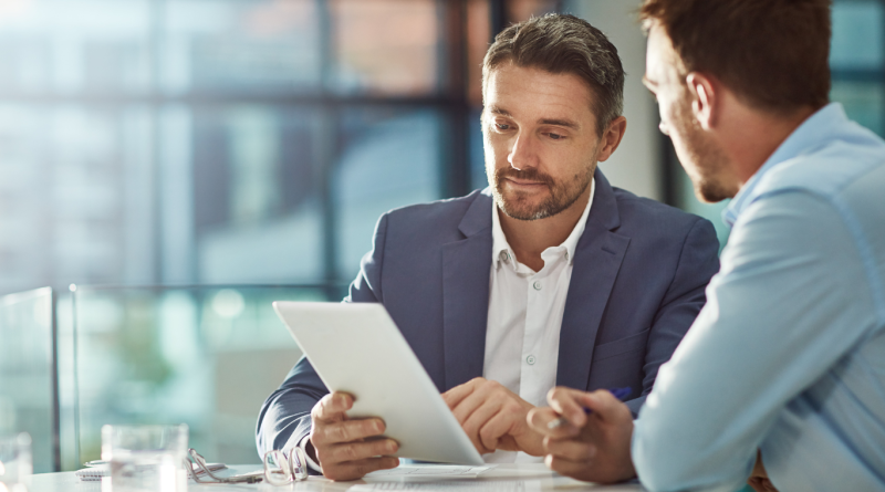 Business professionals reviewing data on a tablet using business management software.