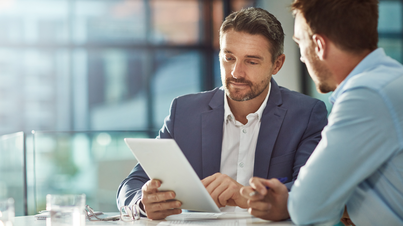 Business professionals reviewing data on a tablet using business management software.