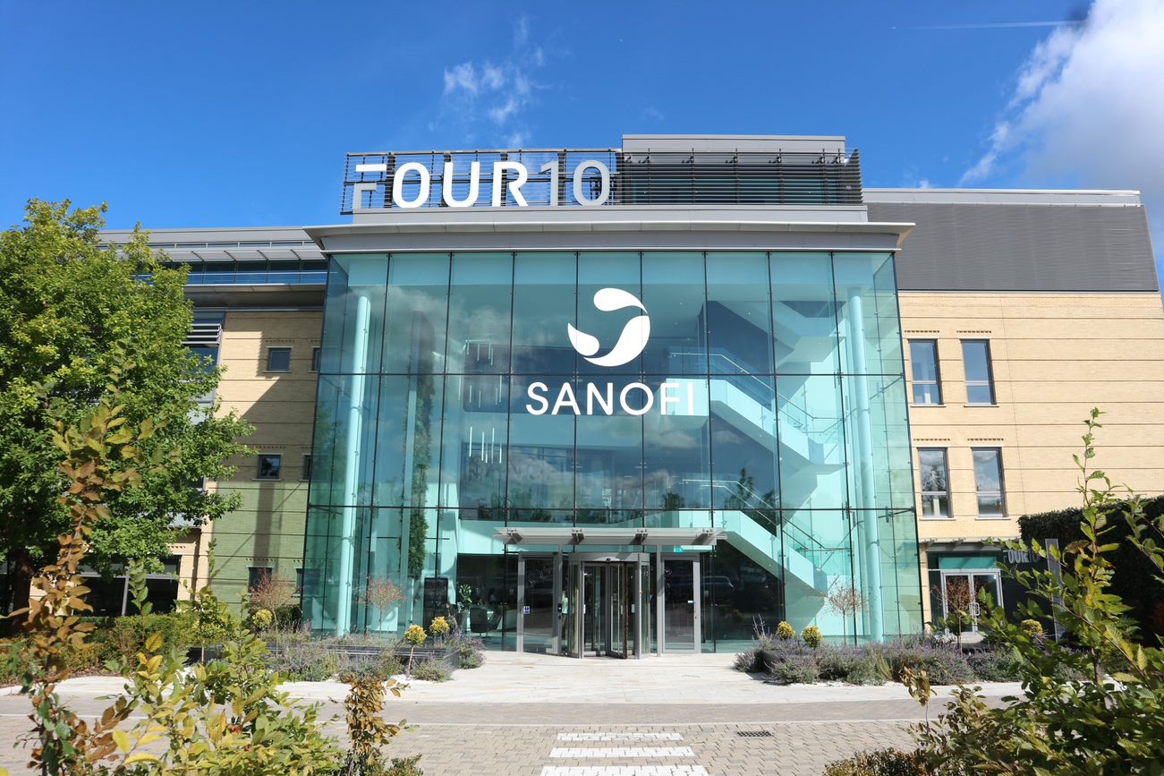 Sanofi corporate building with Blueprint Medicines logo overlay and DNA helix graphic symbolizing biotech investment