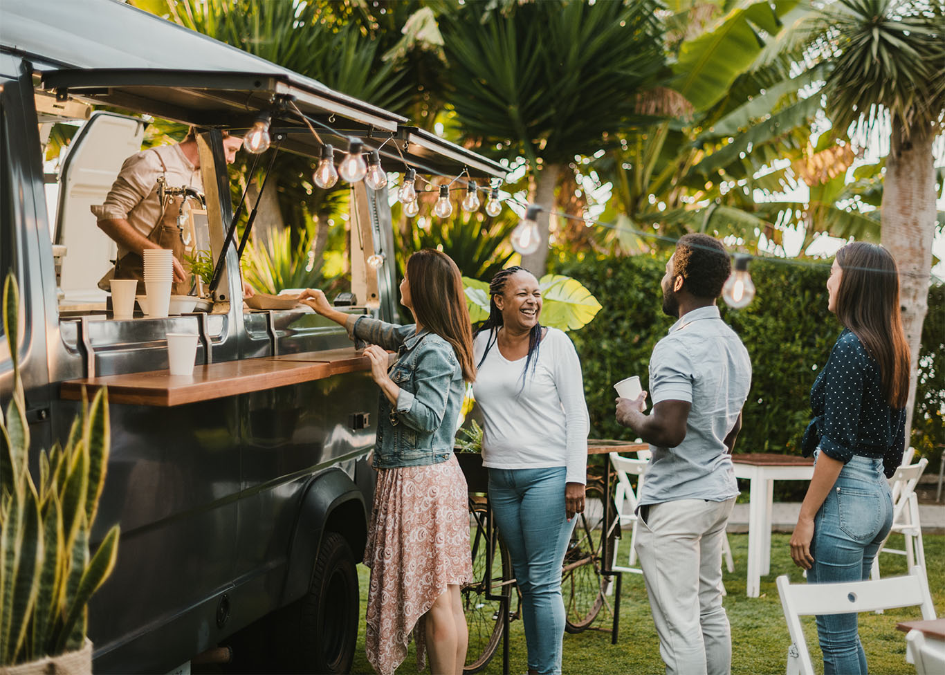 A food truck with camera equipment surrounded by a crowd waiting to perform or order food