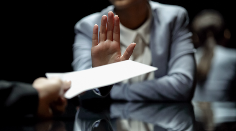 Professional woman in a business suit raising her hand to refuse or reject a document being offered across a desk during a meeting, symbolizing turning down a job offer or salary proposal.