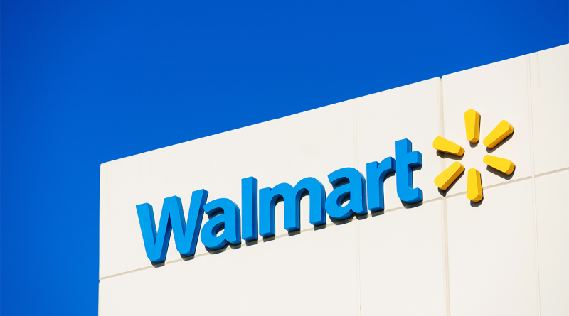 Walmart logo mounted on the exterior of a store building against a clear blue sky.